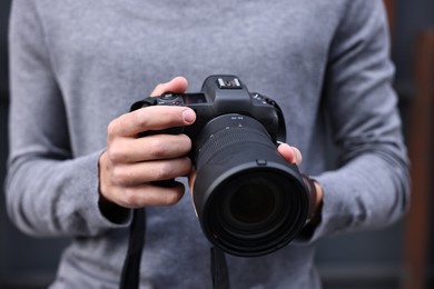 Photo of Professional photographer with modern camera outdoors, closeup