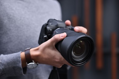 Photo of Professional photographer with modern camera outdoors, closeup