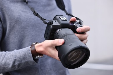 Photo of Professional photographer with modern camera outdoors, closeup