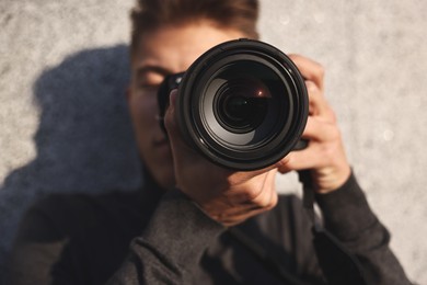 Photo of Professional photographer taking picture with camera outdoors, selective focus