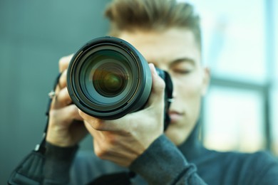 Photo of Professional photographer taking picture with camera outdoors, selective focus