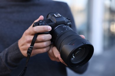 Photo of Professional photographer with modern camera outdoors, closeup