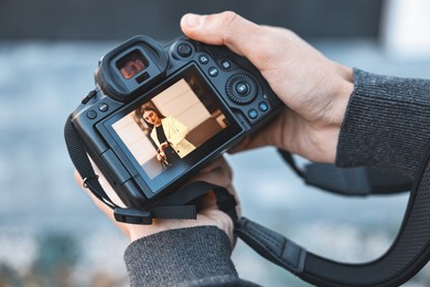 Photo of Professional photographer with modern camera outdoors, closeup