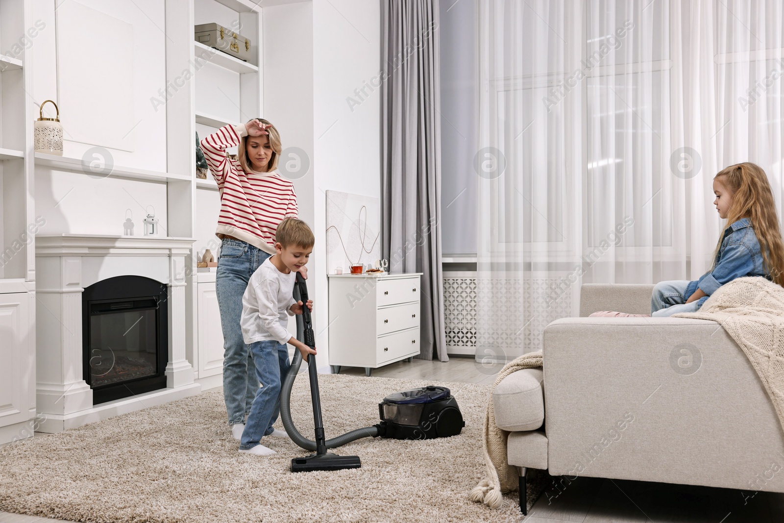 Photo of Housewife and her kids cleaning room together