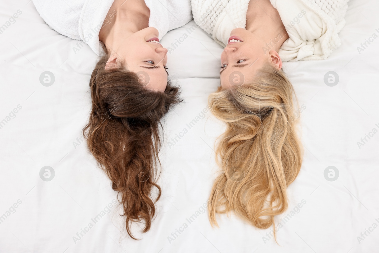 Photo of Spa day. Happy women lying on bed, above view