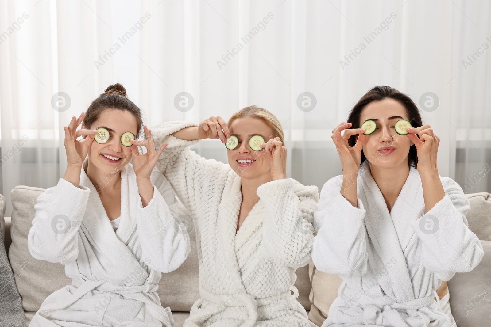 Photo of Happy women with cucumber slices on sofa in spa