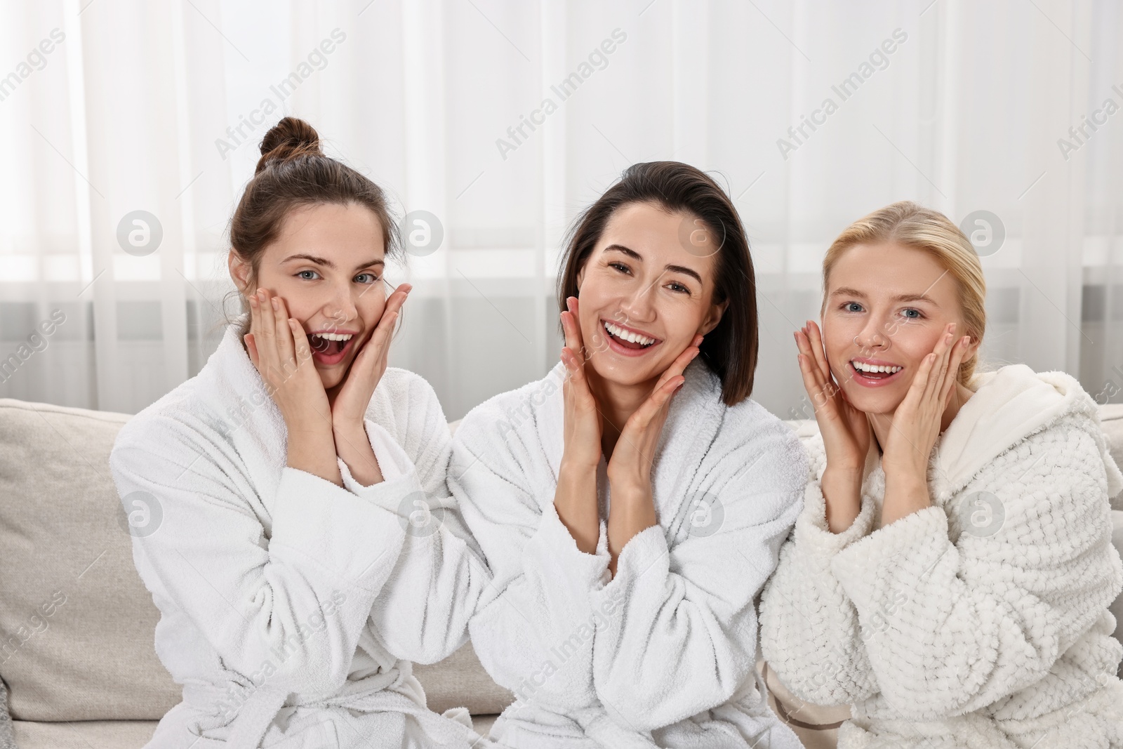 Photo of Happy woman wearing bathrobes on sofa in spa