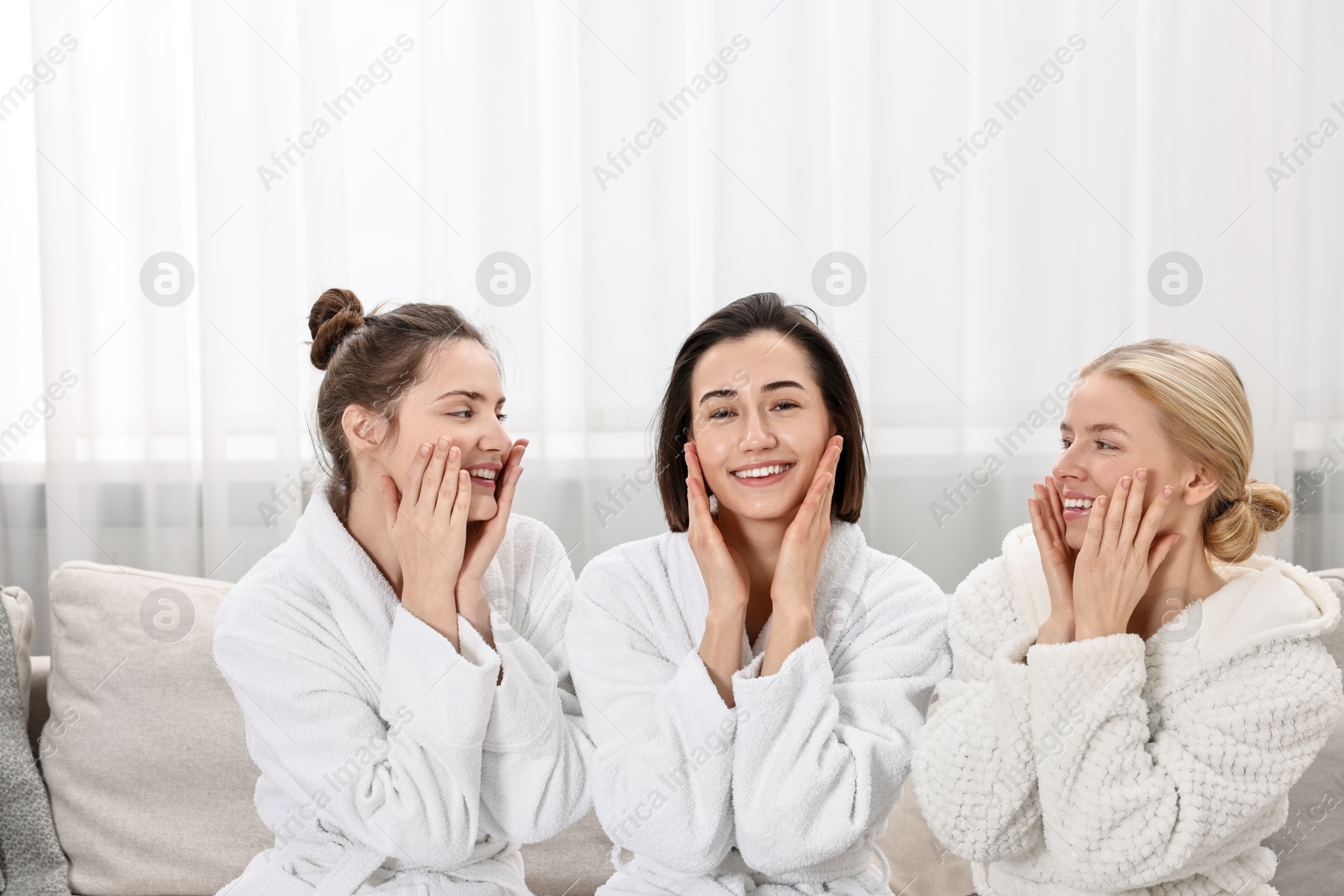 Photo of Happy woman wearing bathrobes on sofa in spa