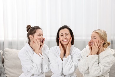 Photo of Happy woman wearing bathrobes on sofa in spa