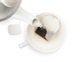 Photo of Pouring hot water into cup with tea bag on white background, top view