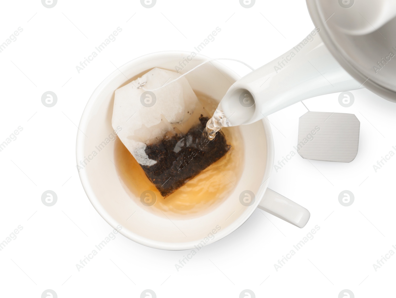 Photo of Pouring hot water into cup with tea bag on white background, top view