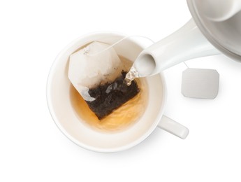 Photo of Pouring hot water into cup with tea bag on white background, top view