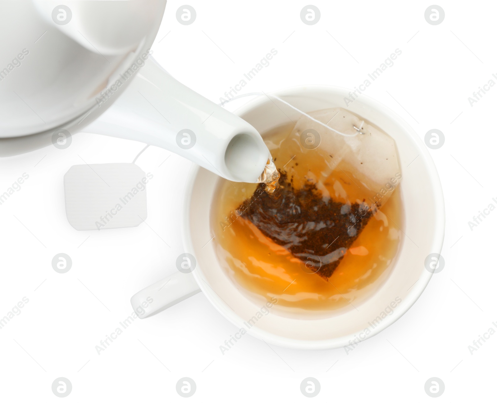 Photo of Pouring hot water into cup with tea bag on white background, top view