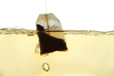 Photo of Putting tea bag into glass cup on white background, closeup