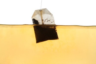 Photo of Putting tea bag into glass cup on white background, closeup