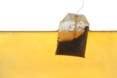 Photo of Putting tea bag into glass cup on white background, closeup