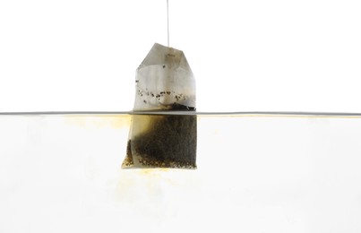 Photo of Putting tea bag into glass cup on white background, closeup