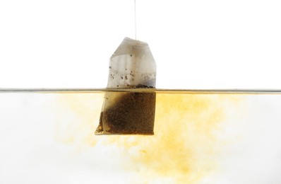 Photo of Putting tea bag into glass cup on white background, closeup