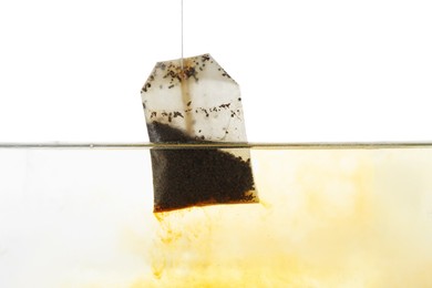 Photo of Putting tea bag into glass cup on white background, closeup