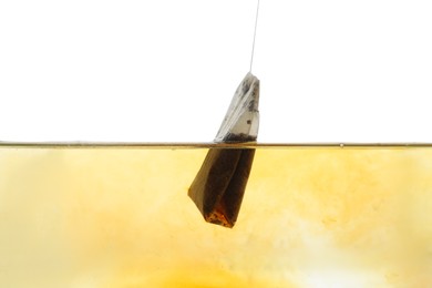 Photo of Putting tea bag into glass cup on white background, closeup