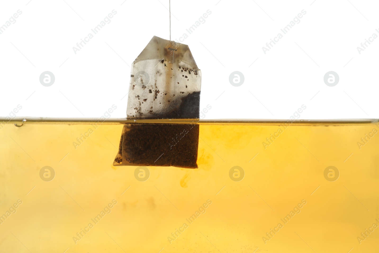 Photo of Putting tea bag into glass cup on white background, closeup