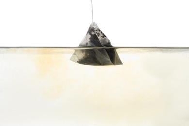 Photo of Putting tea bag into glass cup on white background, closeup