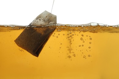 Photo of Putting tea bag into glass cup on white background, closeup