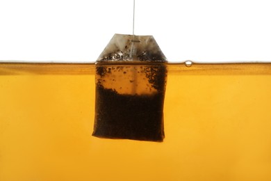 Photo of Putting tea bag into glass cup on white background, closeup