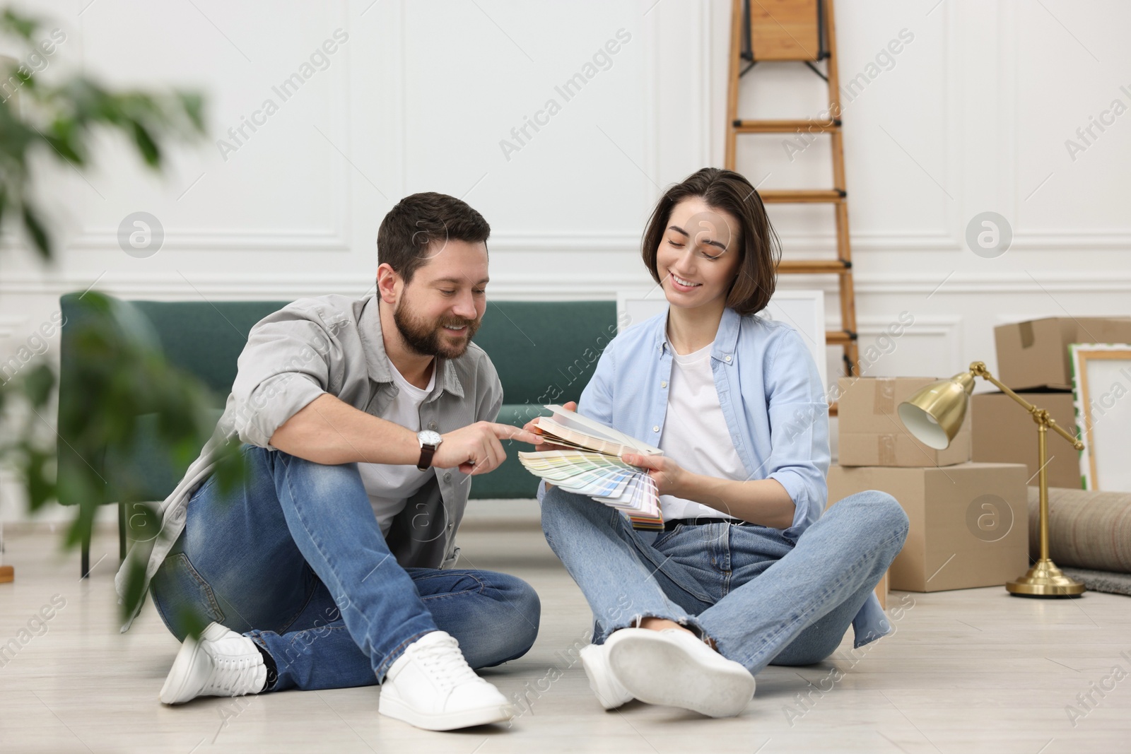 Photo of Moving day. Happy couple choosing paint color for their new home