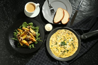 Photo of Tasty brunch. Delicious omelette, fried potatoes and coffee served on black textured table, flat lay