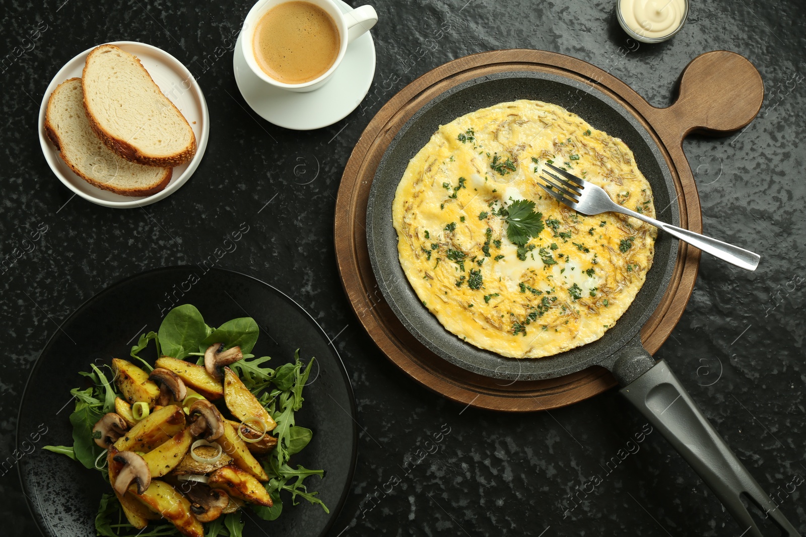 Photo of Tasty brunch. Delicious omelette, fried potatoes and coffee served on black textured table, flat lay