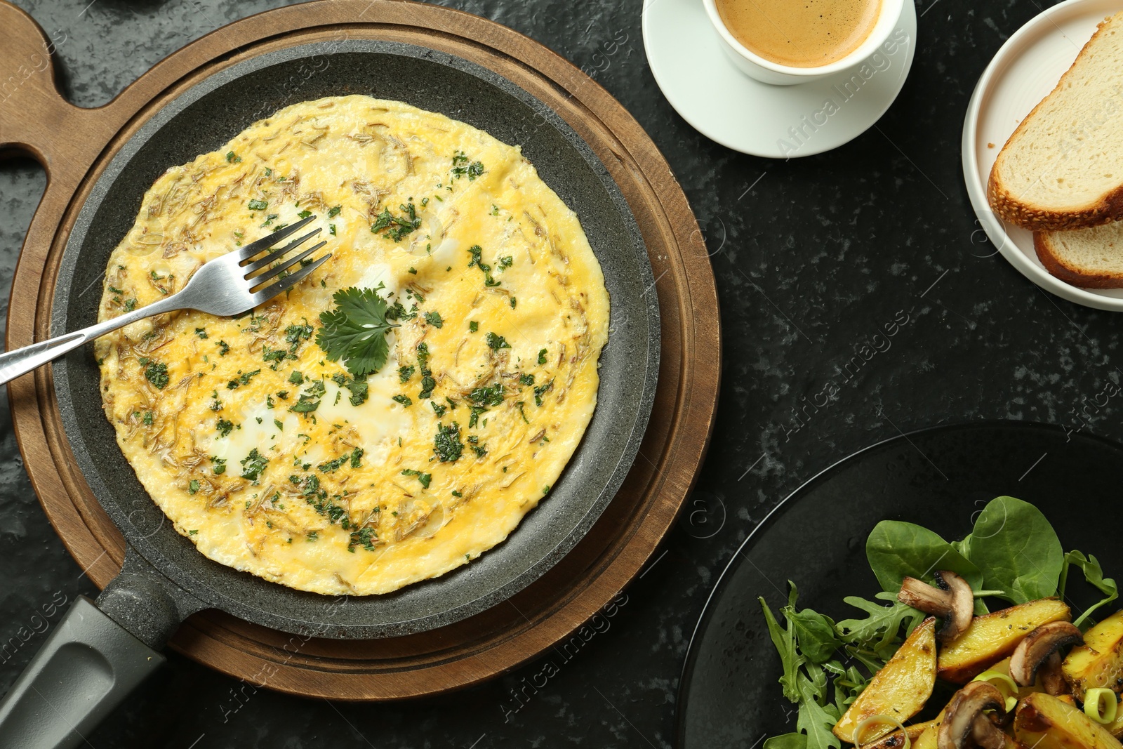 Photo of Tasty brunch. Delicious omelette, fried potatoes and coffee served on black textured table, flat lay