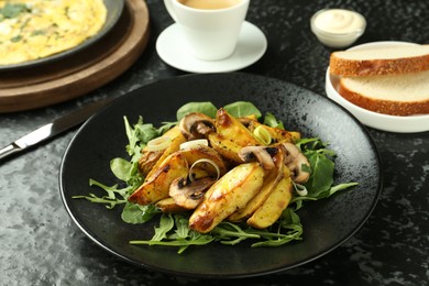 Photo of Tasty brunch. Delicious fried potatoes with arugula and mushrooms served on black textured table, closeup