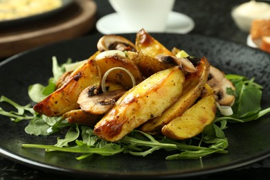 Photo of Tasty brunch. Delicious fried potatoes with arugula and mushrooms served on table, closeup