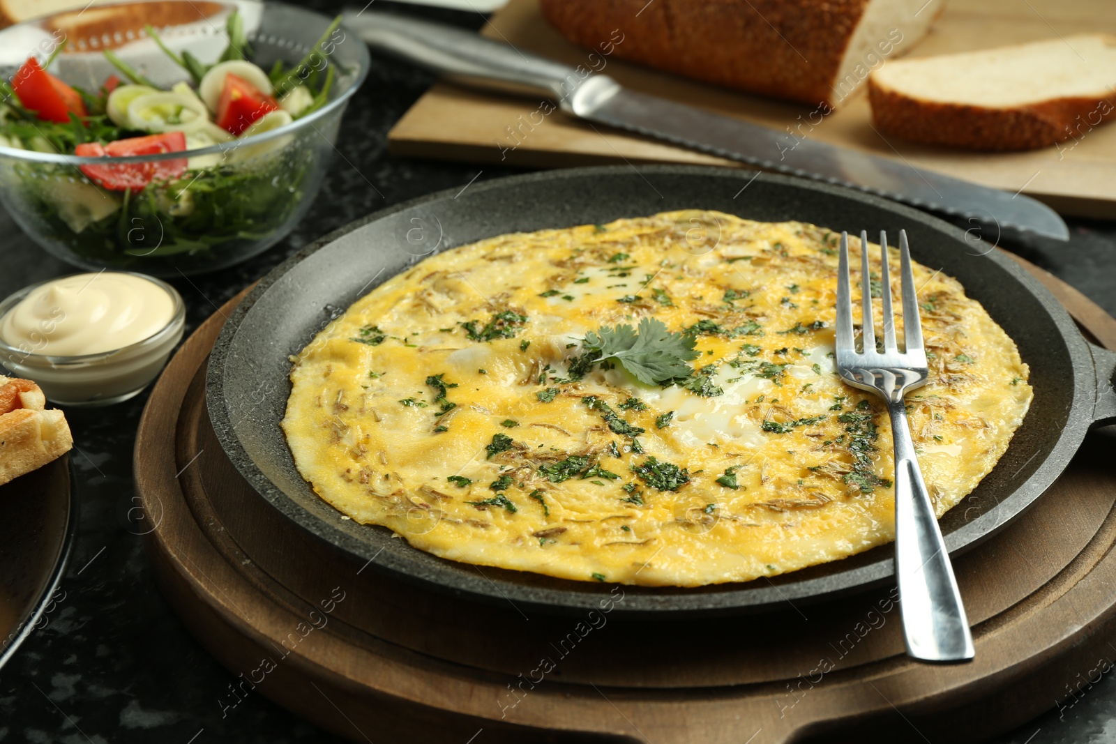 Photo of Tasty brunch. Delicious omelette and salad served on black textured table, closeup