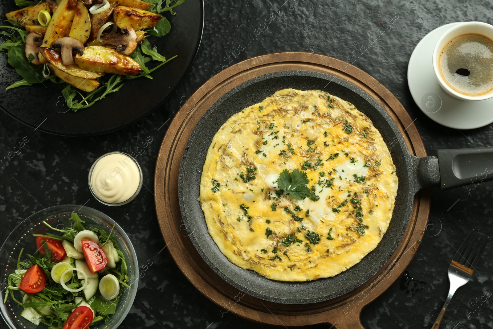 Photo of Tasty brunch. Delicious omelette, salad, fried potatoes and coffee served on black textured table, flat lay