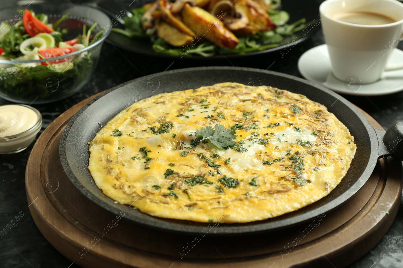 Photo of Tasty brunch. Delicious omelette, salad, fried potatoes and coffee served on black textured table, closeup