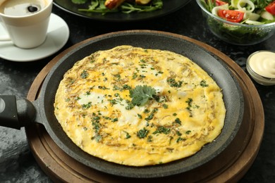 Photo of Tasty brunch. Delicious omelette, salad and coffee served on black textured table, closeup