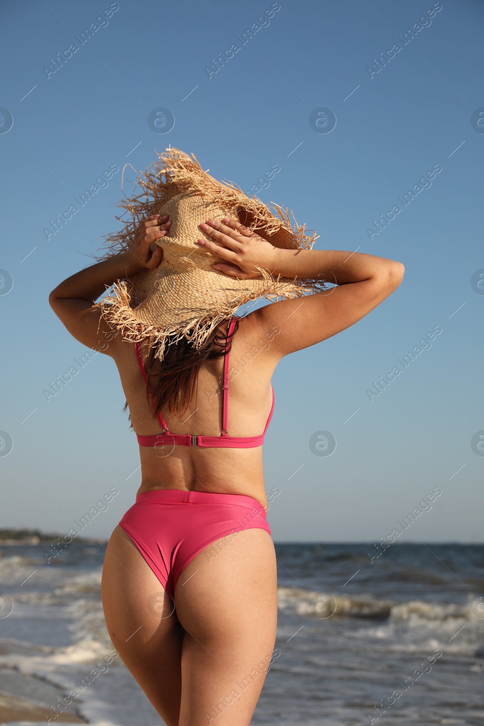 Photo of Young woman with attractive body on beach, back view