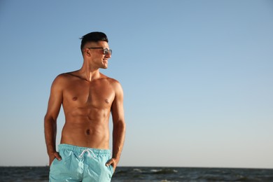 Photo of Handsome man with attractive body on beach. Space for text