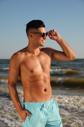 Photo of Handsome man with attractive body on beach