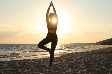 Photo of Young girl with slim body doing yoga on beach