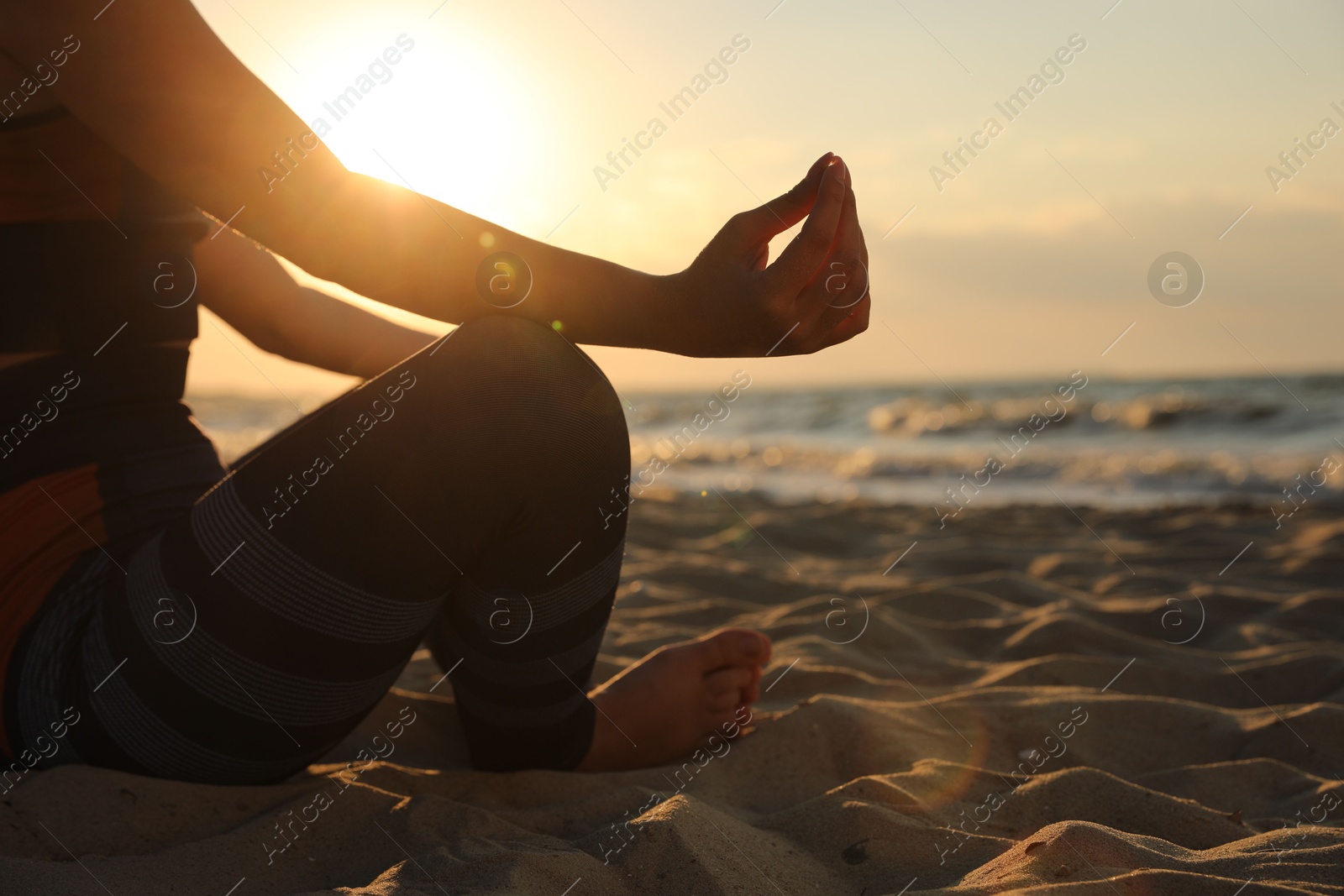 Photo of Young girl doing yoga on beach at sunset, closeup