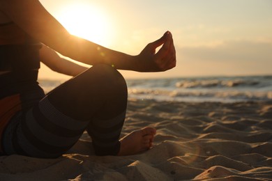 Photo of Young girl doing yoga on beach at sunset, closeup