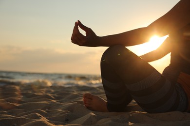 Photo of Young girl doing yoga on beach at sunset, closeup