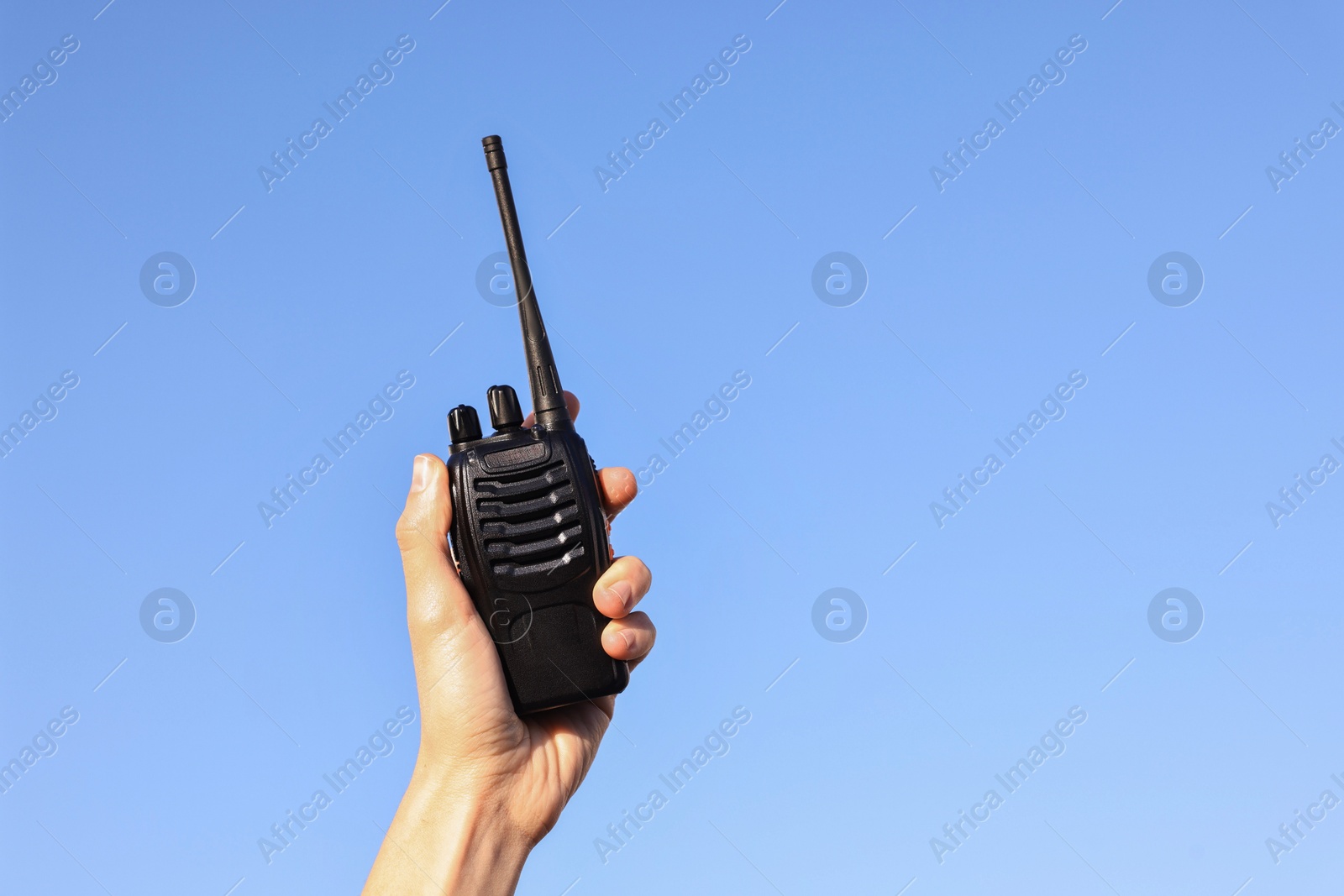 Photo of Woman with walkie talkie against blue sky outdoors, closeup. Space for text