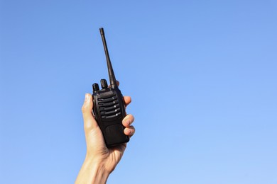 Photo of Woman with walkie talkie against blue sky outdoors, closeup. Space for text