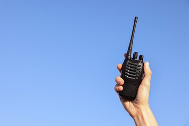 Photo of Woman with walkie talkie against blue sky outdoors, closeup. Space for text