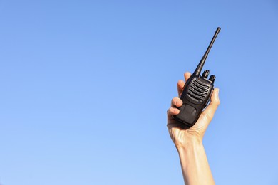 Photo of Woman with walkie talkie against blue sky outdoors, closeup. Space for text