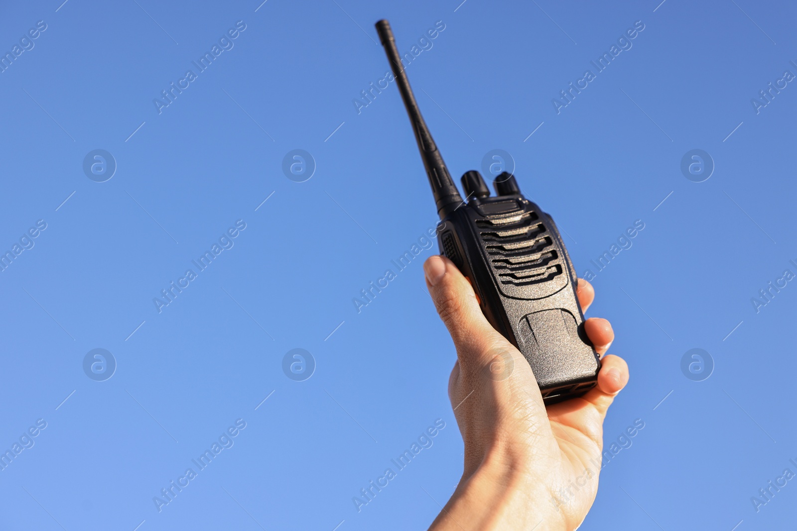 Photo of Woman with walkie talkie against blue sky outdoors, closeup. Space for text